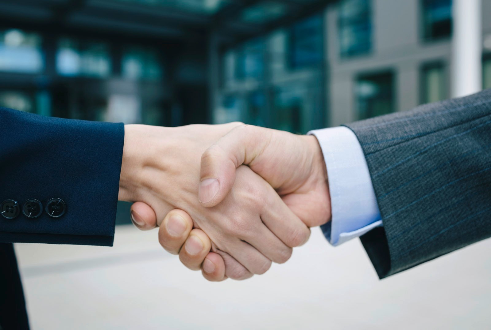 Handshake between two business people in suits - symbol of partnership in the e-mobilio partner program
