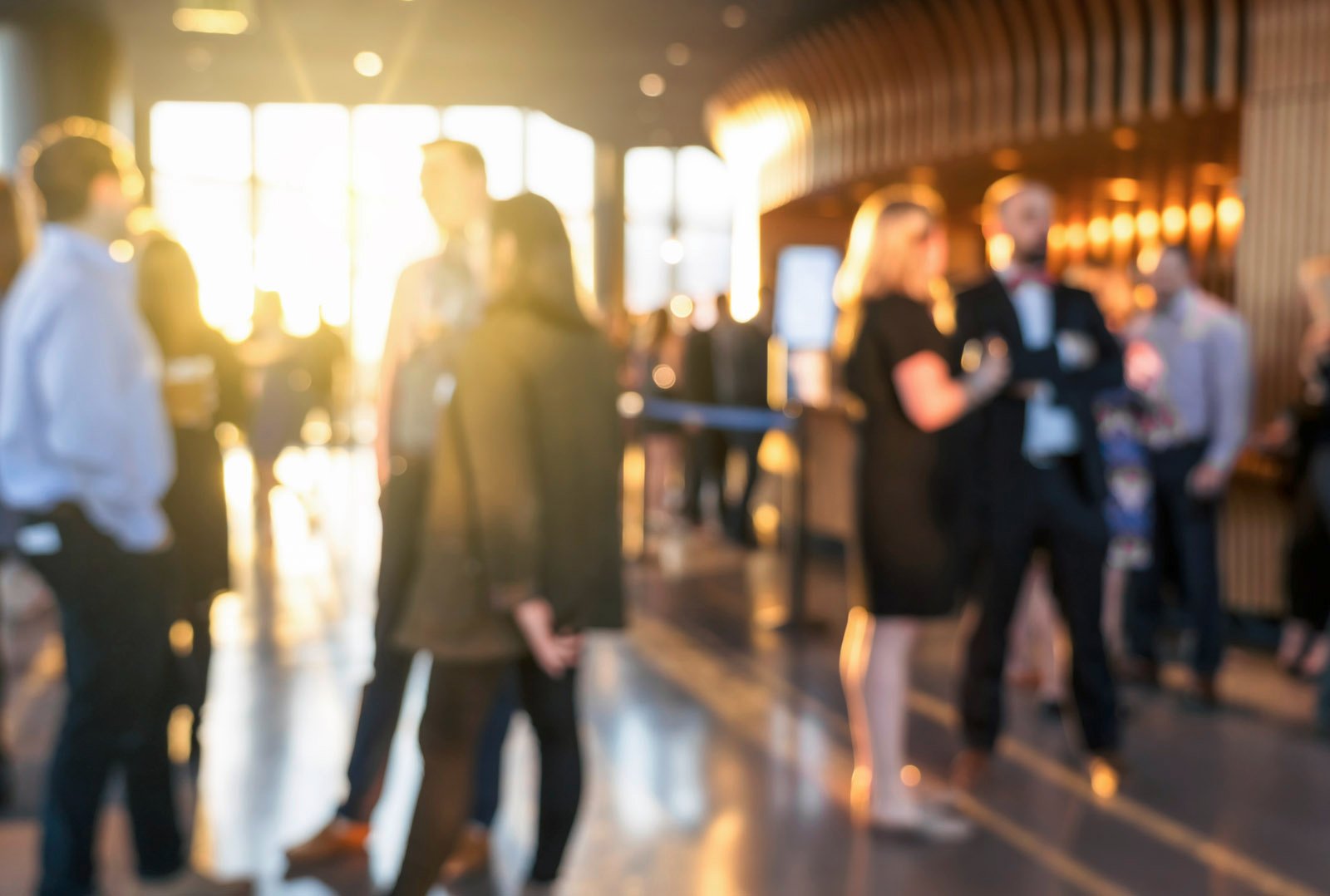 People at an event in a modern car dealership, in conversation and in sunlight - symbolizing events related to electromobility