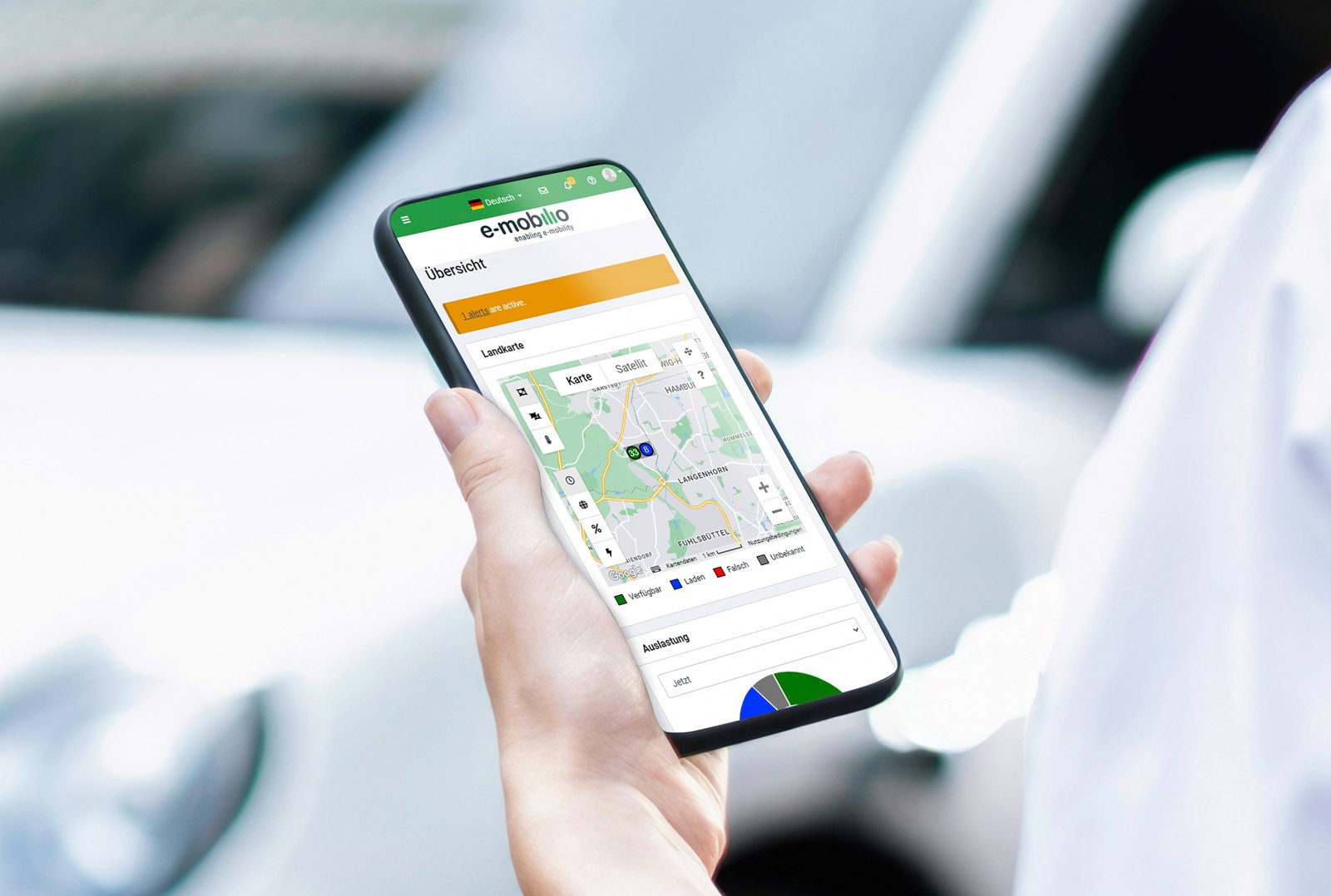 Hand holds smartphone with e-mobilio billing app for managing charging processes via card and location selection