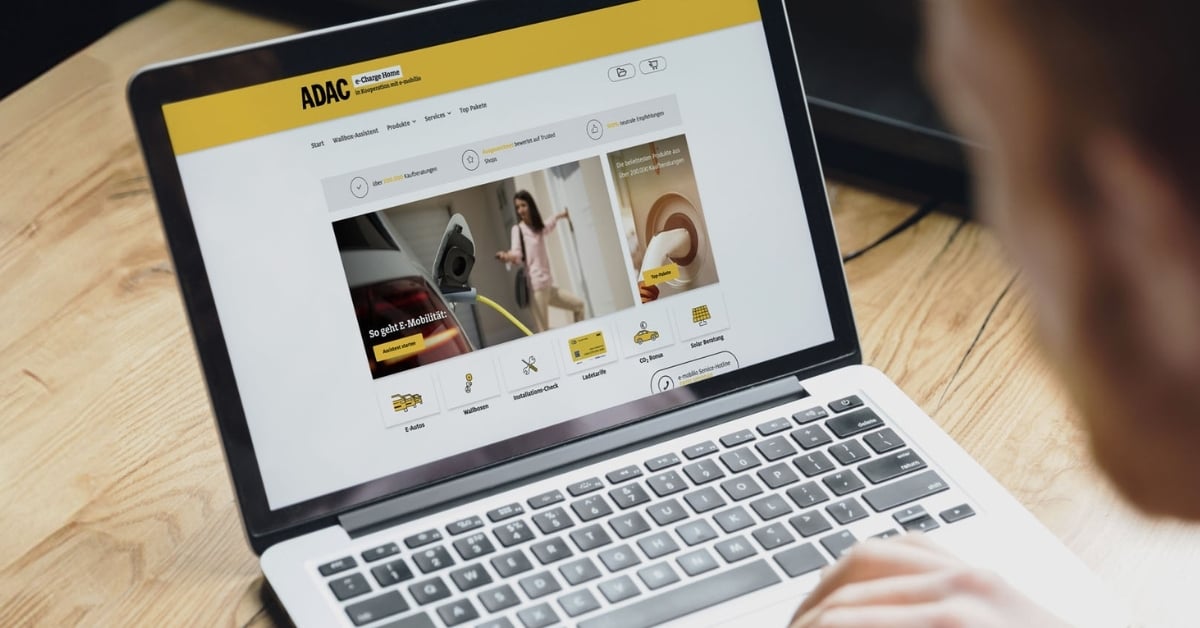 View from the back left of a man looking at a laptop on which the ADAC blog article on the cooperation with e-mobilio is displayed